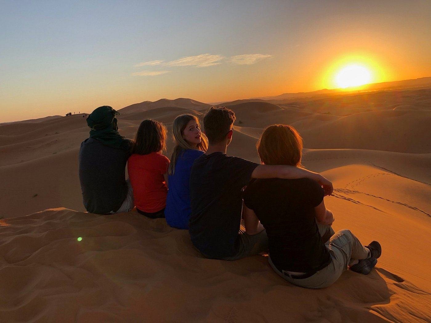 A family watching the sunset on the dunes of the Sahara